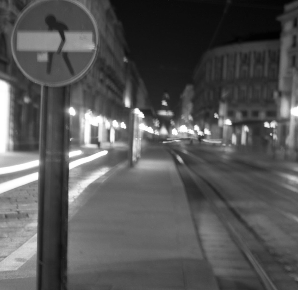 Cartello stradale con disegno ironico a Milano di notte