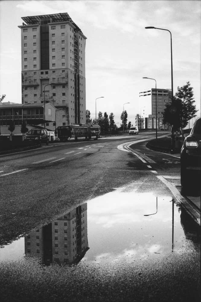 Un palazzo si riflette in una pozzanghera a milano
